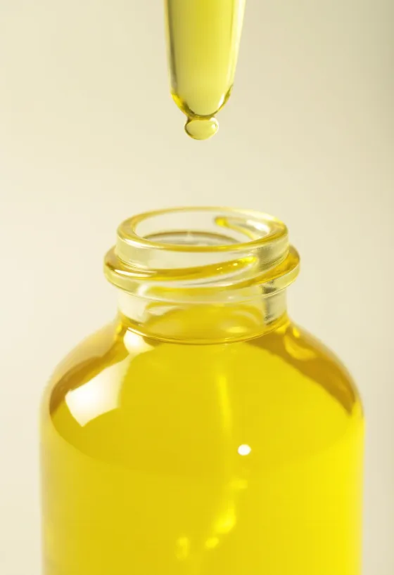 Citrónový olej v malej fľaštičke, vedľa čerstvých plátkov citróna a nastrúhanej kôry